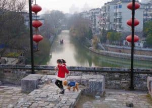 Late in the afternoon, a girl and her dog play along the old course of the Nanjing city wall.