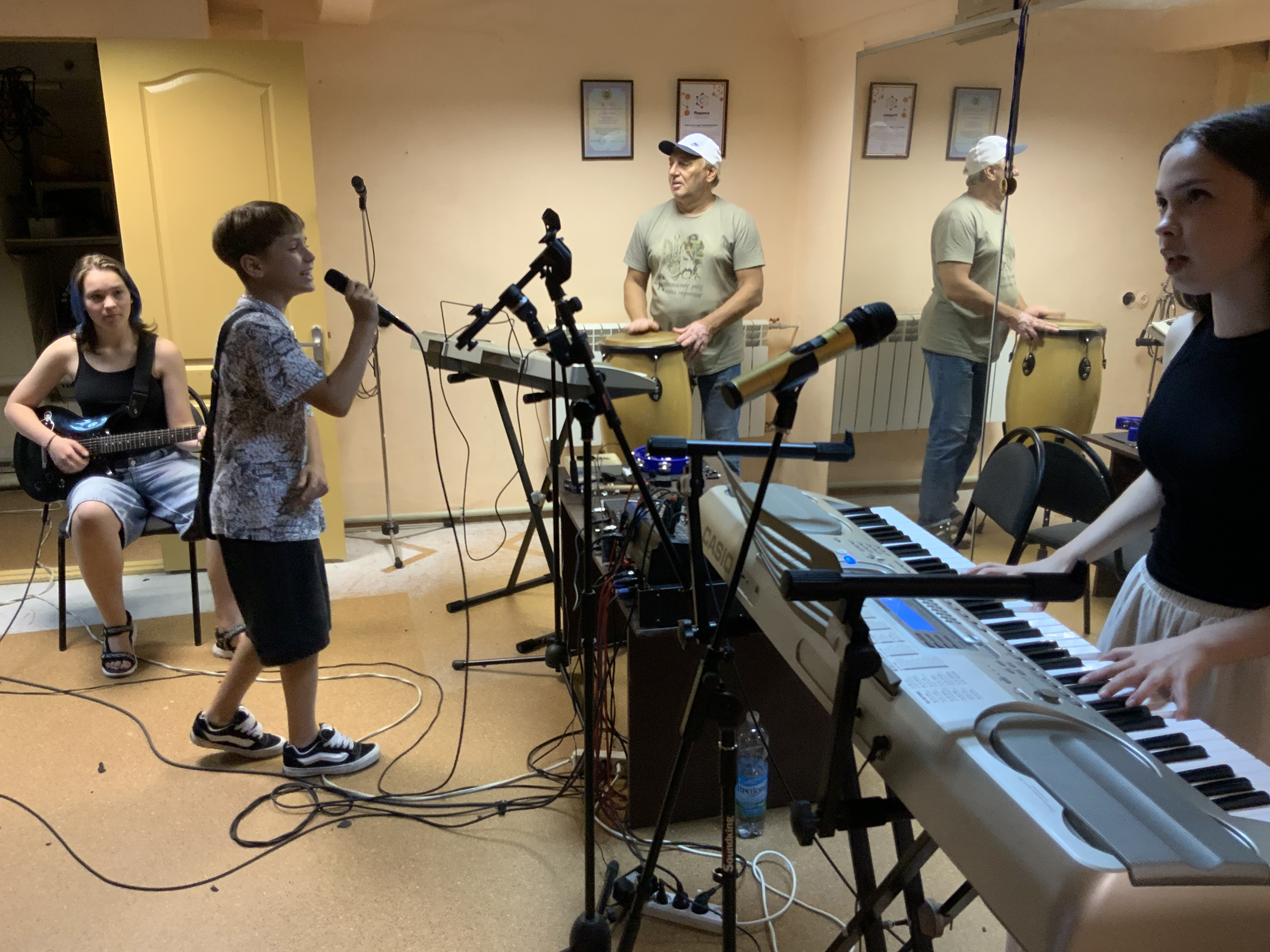 The band Teenager Stars, in Kharkiv. Ten year-old Daniil is singing, to his left, Lisa is on the drums, and to his right, Iryna is on the organ. The organiser, Yuri Mischenko, is in the back, playing the drums.